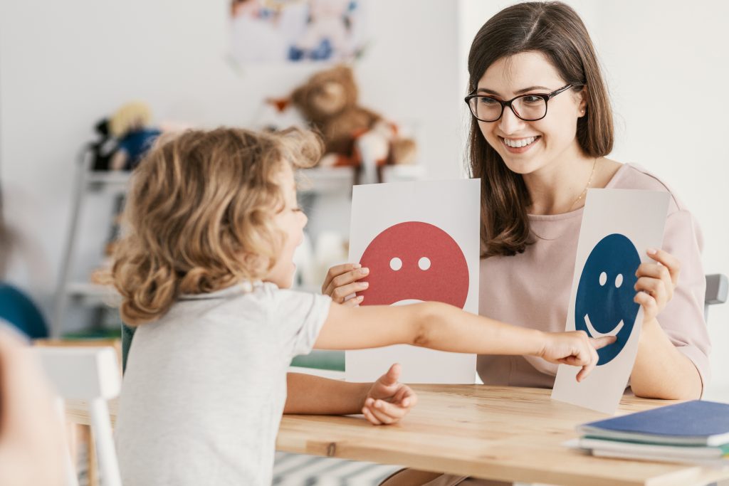 A counselor working with a child pointing to feeling cards